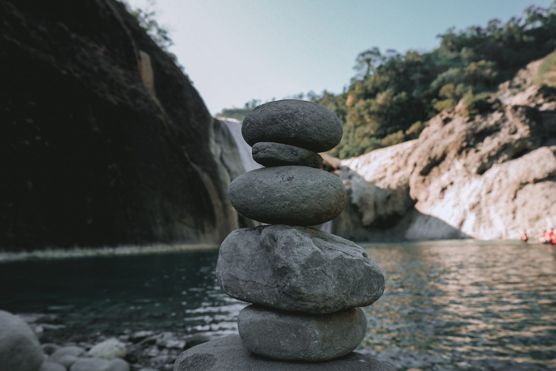 A serene stack of stones by a tranquil waterfall in a lush outdoor setting.